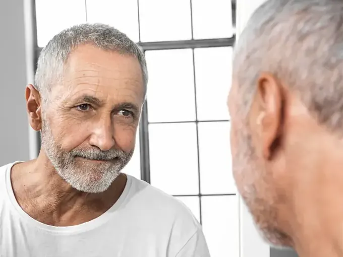 Homem observando sinais de calvície no espelho